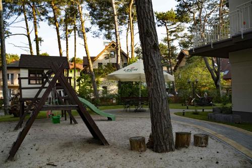 a playground with a slide and an umbrella and a tree at Pensjonat i Restauracja Laguna in Pogorzelica