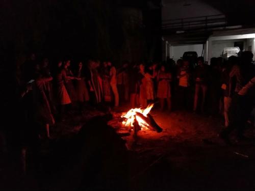 un grupo de personas de pie alrededor de un fuego en Rexon Residency, en Kattappana