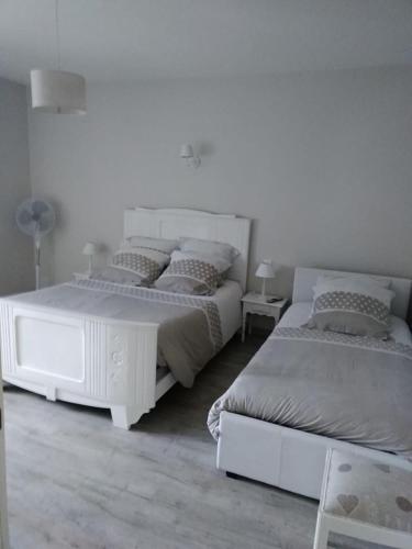 a white bedroom with two beds and a lamp at GITE IZALIN AVEC SPA A 20 min du Puy du Fou in Mauléon
