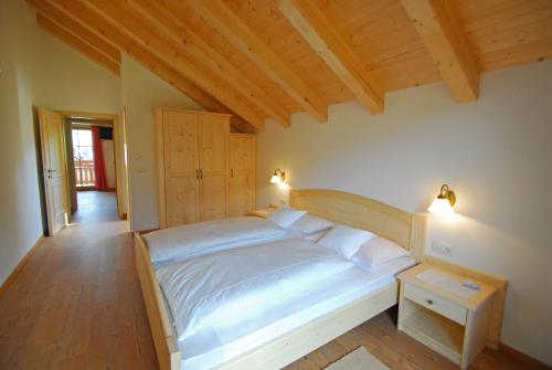 a bedroom with a white bed and a wooden floor at Oberkantiolhof in Villnoss