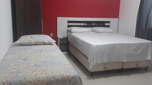 2 camas num quarto com uma parede vermelha em PRADO-CARIBE DO NORDESTE: CASA TEMPORADA!!! em Prado