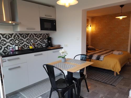 - une petite cuisine et une table dans une chambre avec un lit dans l'établissement Le P'tit gousset, à 100 m de la mer, à Donville-les-Bains