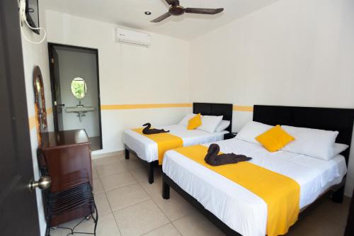 two beds in a room with yellow and white at Nicol-Haa in Izamal