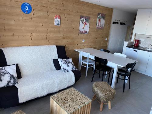 un salon avec un canapé et une table avec des chaises dans l'établissement Plagne Centre - Immeuble Le Mustag - Wifi, à Aime La Plagne