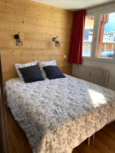 een slaapkamer met een bed met een houten muur bij Plagne Centre - Immeuble Le Mustag - Wifi in Aime La Plagne