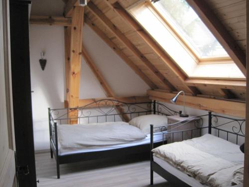two beds in a attic room with a window at Ferienhaus auf dem Hof Lechner in Drieschnitz