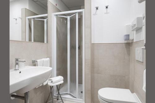 a white bathroom with a toilet and a sink at Hotel Martini in Verona