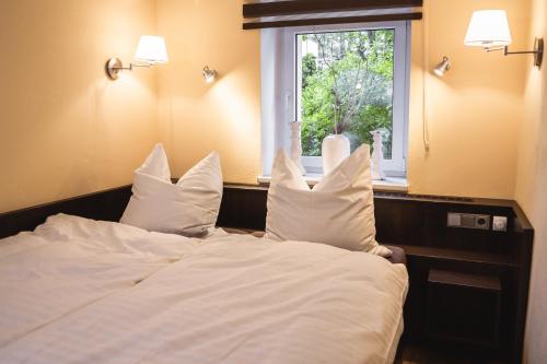 una camera da letto con un letto con cuscini bianchi e una finestra di athome IHR Apartment a Chemnitz