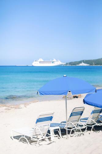 a group of chairs and an umbrella on a beach at Sand Castle on the Beach - Adults Only in Frederiksted