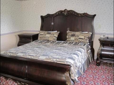 1 dormitorio con 1 cama de madera y 2 mesitas de noche en The Parsippany Inn and Suites, en Morris Plains