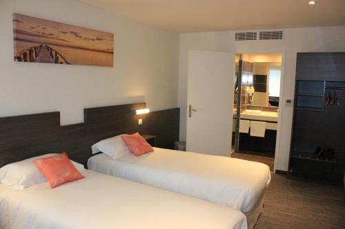 a hotel room with two beds and a bathroom at Hôtel Restaurant Bel Air Crevin - Axe Rennes Nantes in Crévin