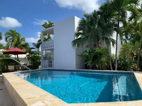 a swimming pool in front of a building with palm trees at Sand Castle on the Beach - Adults Only in Frederiksted