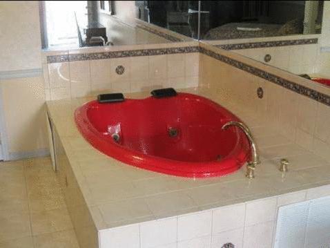 y baño con bañera roja y lavabo rojo. en The Parsippany Inn and Suites, en Morris Plains