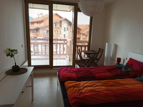 a living room with a couch and a large window at Emerald Buddha Apartment in Bansko