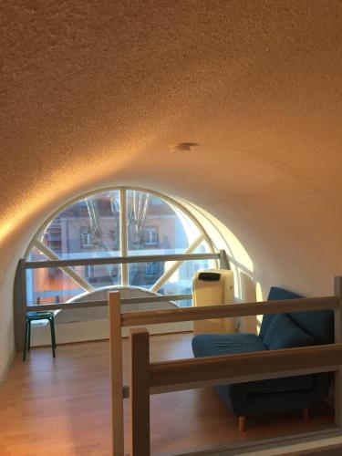 a room with an arched window and a wooden bench at les magnolias in Colmar