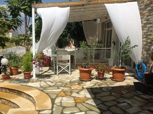 a patio with potted plants and a white canopy at Neaktion Apartments in Nikiti
