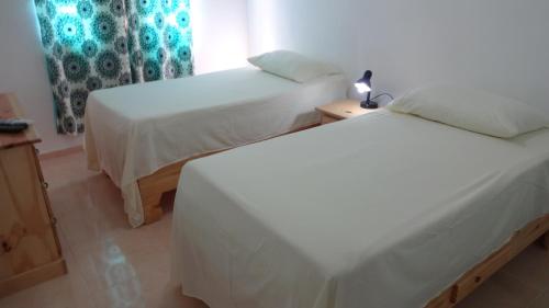 a bedroom with two beds and a lamp on a table at Aparta hotel El Sol, Home near AirPort SDQ in Boca Chica