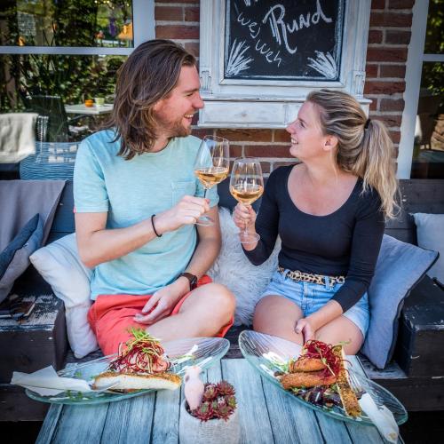 a man and woman sitting on a table with glasses of wine at De Stobbe hotel & suites in Ruinen