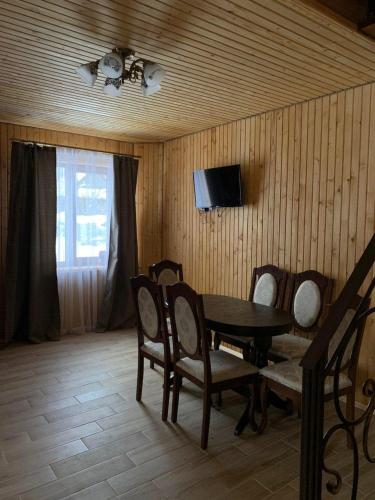 a dining room with a table and chairs and a television at Шервуд in Myta