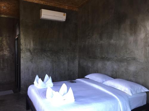 a bed with white pillows on it in a room at ชลลดา ริเวอร์ โฮมสเตย์ แก่งกระจาน in Ban Wang Malako