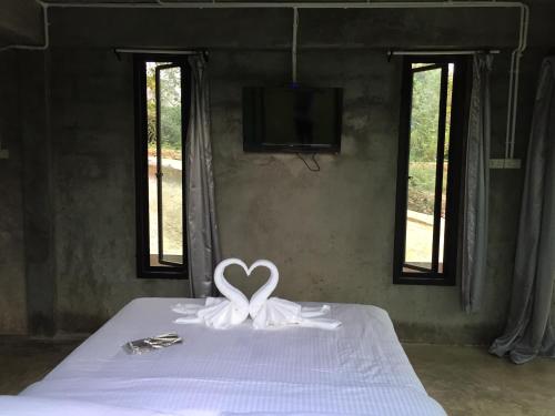 a white heart bow on a bed with windows at ชลลดา ริเวอร์ โฮมสเตย์ แก่งกระจาน in Ban Wang Malako