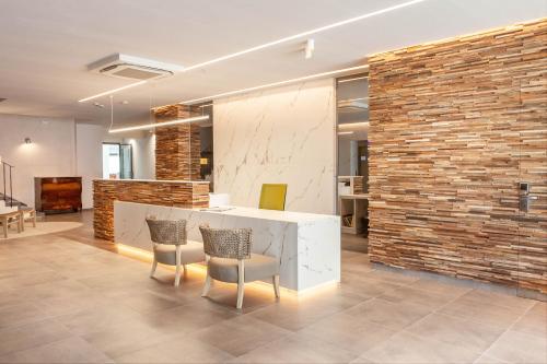 un hall avec un comptoir, des chaises et un mur en briques dans l'établissement Hotel Montecarlo Spa & Wellness, à Roses