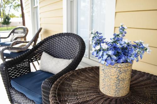 a wicker chair and a table with a vase of blue flowers at Das Meyer Haus - Luxe Victorian in Schulenburg