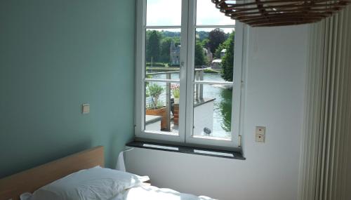 een slaapkamer met een raam met uitzicht op een rivier bij Gîte Bord de Meuse in Namen