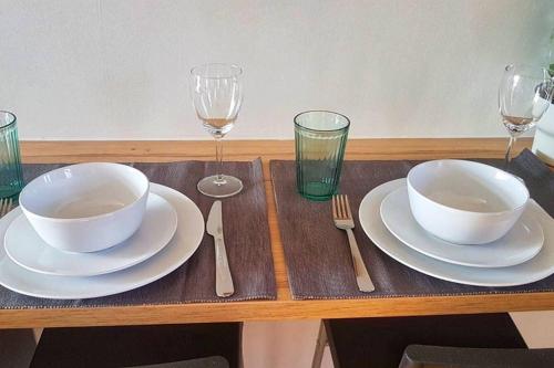 a wooden table with two plates and wine glasses at Modern Studio Apartment Near Town Centre in Poole