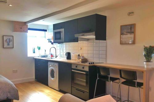 eine Küche mit blauen Schränken, einer Waschmaschine und einem Trockner in der Unterkunft Modern Studio Apartment Near Town Centre in Poole