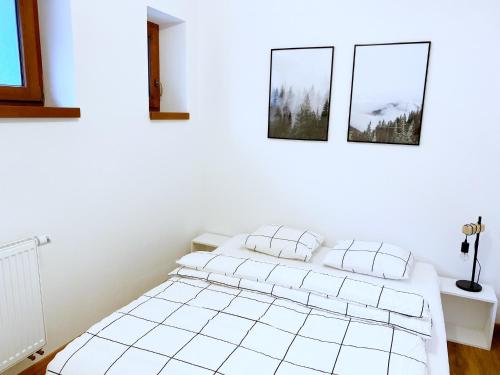 a white bedroom with two pillows on a bed at Mezonetový apartmán ve skandinávském stylu in Rokytnice nad Jizerou