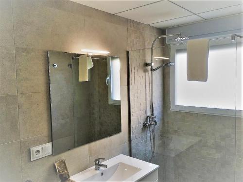 a bathroom with a sink and a shower with a mirror at Tierra Marina Dénia BAJO con jardín in Denia
