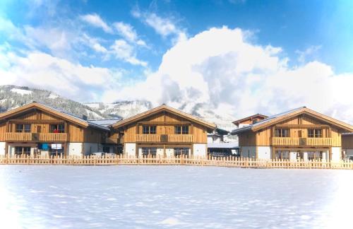 a row of wooden buildings next to a body of water at Sieglhub Chalets - Appartements - Hotel in Flachau