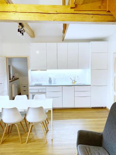 a kitchen with white cabinets and a table and chairs at Mezonetový apartmán ve skandinávském stylu in Rokytnice nad Jizerou