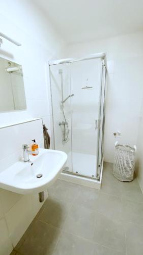 a white bathroom with a shower and a sink at Mezonetový apartmán ve skandinávském stylu in Rokytnice nad Jizerou