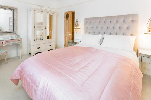 a white bedroom with a pink bed and a sink at Stamford Park Road by YourStays! in Altrincham