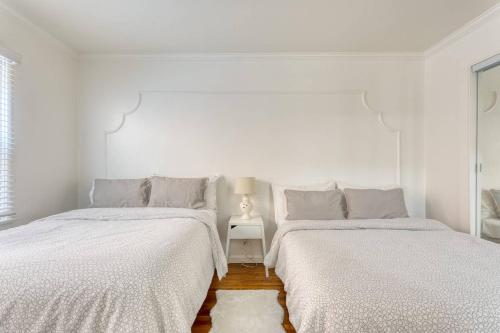 2 Betten in einem Schlafzimmer mit weißen Wänden und Holzböden in der Unterkunft New Beach Jewel Bungalow in Long Beach