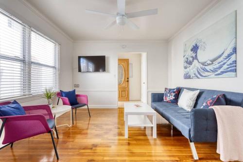 a living room with a blue couch and pink chairs at New Beach Jewel Bungalow in Long Beach