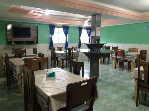 a dining room with tables and chairs and a tv at Pousada Beira Mar in Rio das Ostras