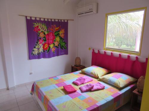 a bedroom with a bed with pink pillows on it at Gite KAZ A LILINE in Le Moule