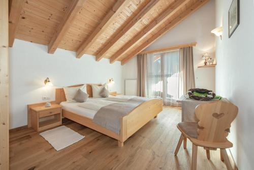 a bedroom with a large bed and a chair at Oberkantiolhof in Villnoss