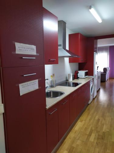 una cocina con armarios rojos y fregadero en Apartamento en el centro de la ciudad 75 metros en Villanueva de la Serena