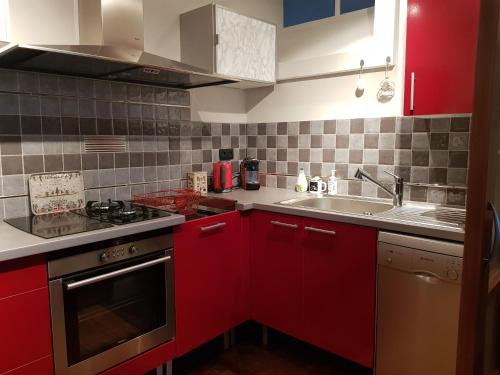 une cuisine avec des armoires rouges et un évier dans l'établissement VANILLE, à Bagnères-de-Bigorre