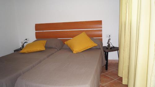 Una cama con dos almohadas amarillas encima. en Domo Sara, en Orosei