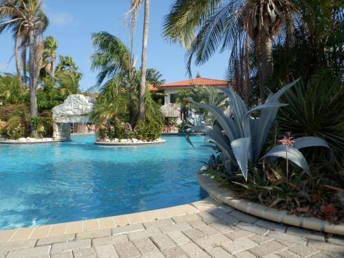 a swimming pool with palm trees in a resort at Seru Coral Resort studio 16 in Willemstad