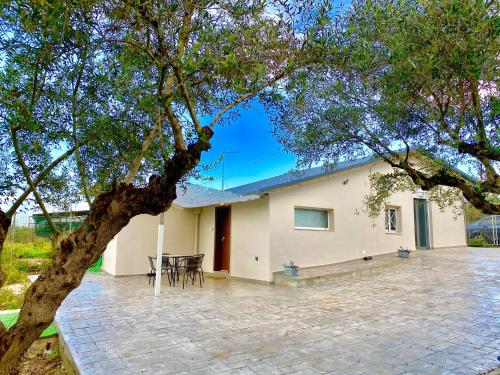 une maison avec une terrasse et un arbre dans l'établissement RIQIONIAN House, à Vromonérion