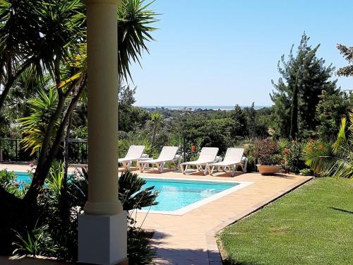 a swimming pool with lounge chairs next to a pole at Villa Crisaflor in Moncarapacho