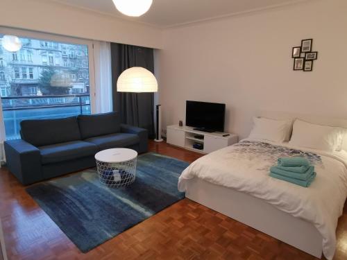 een slaapkamer met een bed, een bank en een televisie bij Florya Studio Woluwe in Brussel