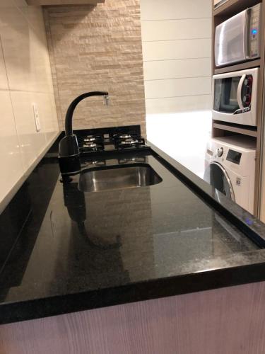 a kitchen counter with a sink and a microwave at Apartamento aconchegante novo in Bento Gonçalves