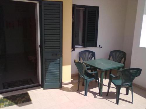 una mesa verde y sillas en una habitación con ventana en Villa Andrea by RENTHOUSESALENTO, en Melendugno